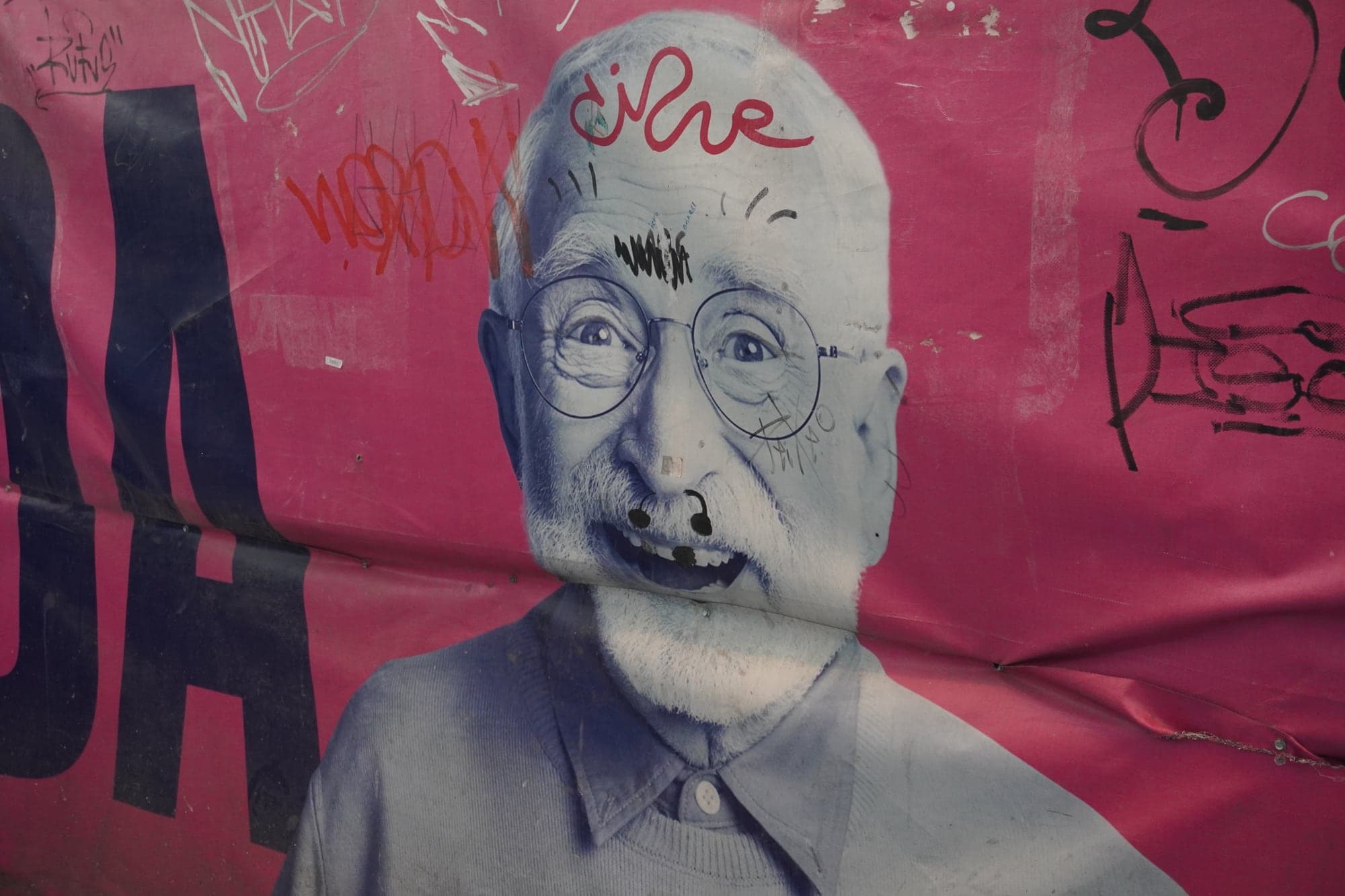 Retrato em graffiti de um homem idoso sobre parede cor-de-rosa.